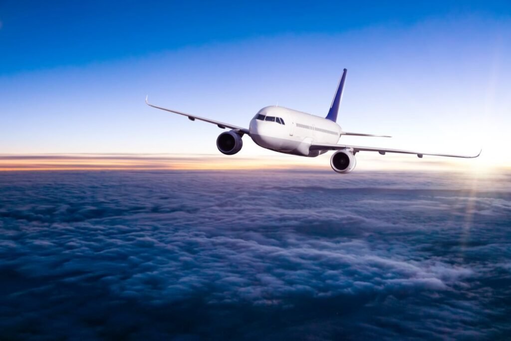 Airplane flying above clouds in dramatic sunset